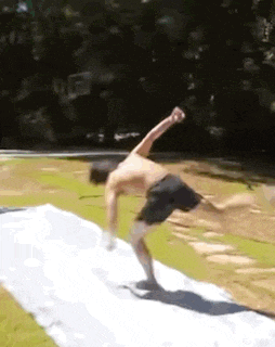 a shirtless man is doing a handstand on a wet slide .