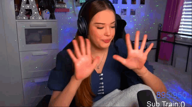 a woman wearing headphones shows off her hands in front of a sign that says 895/950