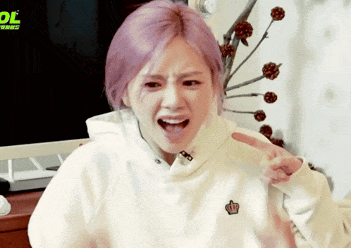 a woman with purple hair is wearing a white sweatshirt with a crown on the chest