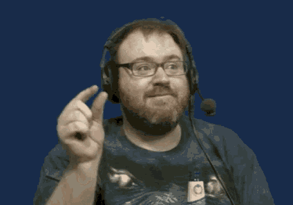 a man with a beard and glasses wearing headphones and a microphone is pointing up .