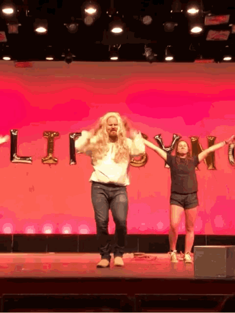 a man in a wig is dancing on a stage in front of a sign that says ' liberty '