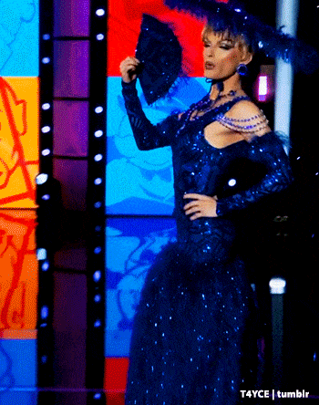 a woman in a blue dress holds a fan in front of a colorful background
