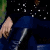 a woman with blonde hair is wearing a black sweater with white polka dots and covering her face with her hand .