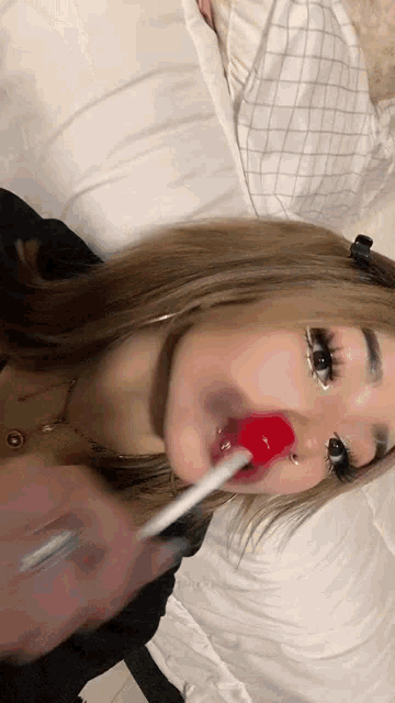 a girl is laying on a bed eating a lollipop .