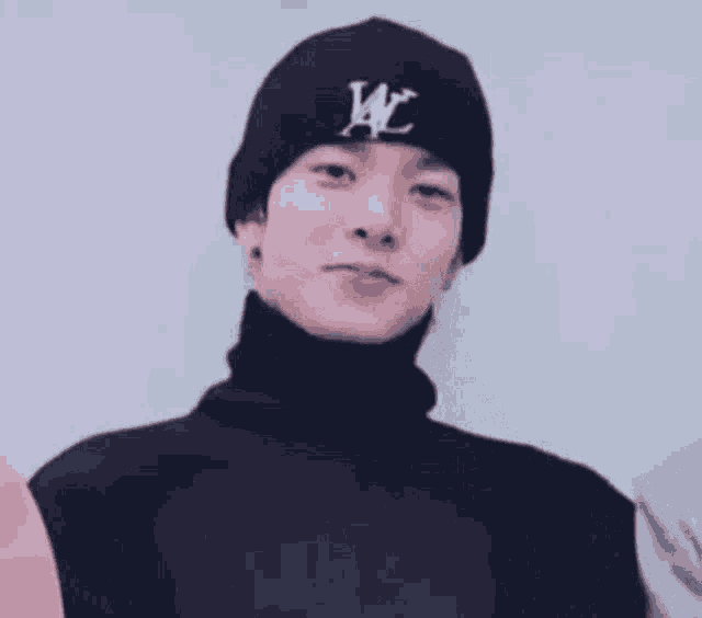 a man wearing a black beanie and a black jacket is making a face .