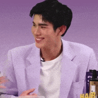 a man wearing a purple jacket and a white t-shirt is smiling .
