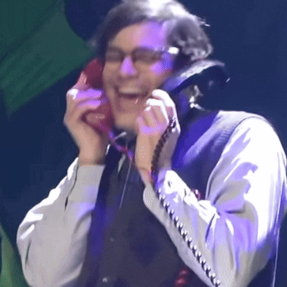 a man in a suit and tie is laughing while talking on a red phone