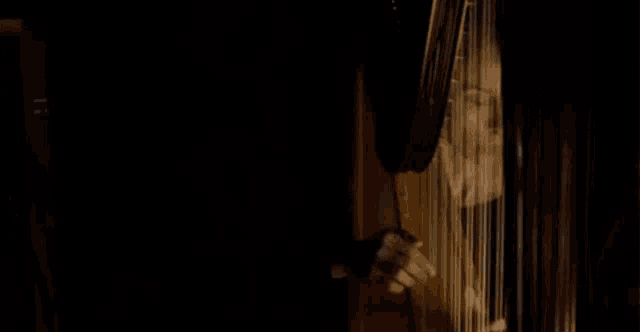a woman is playing a harp in the dark with her eyes closed .