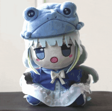 a stuffed doll wearing a frog hat and a blue dress