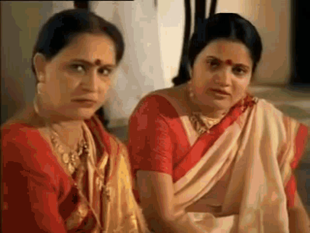 two women are sitting next to each other in a room and looking at each other .