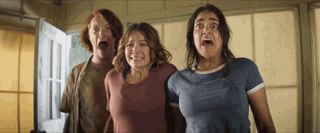 three women are standing in a room with their mouths wide open