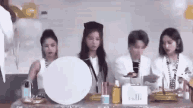a group of women are sitting at a table with balloons and a mirror .