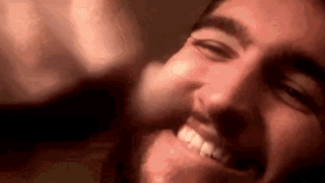 a close up of a man 's face with a beard laughing and smiling .