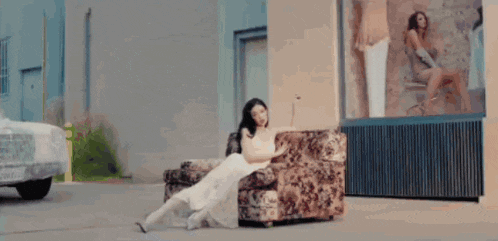 a woman in a white dress is sitting on a couch .