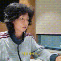 a woman wearing a grey jacket with red stripes on the sleeves is sitting at a table