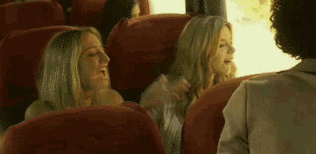 a group of women are sitting in red seats on a bus .