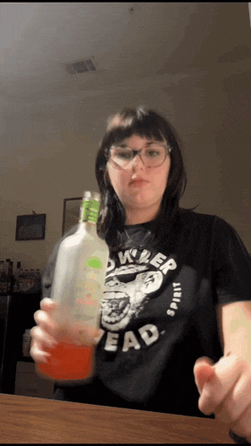 a woman wearing a black shirt that says killer head is holding a bottle
