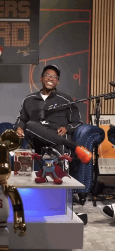 a man sitting on a couch with his legs crossed in front of a sign that says ' warriors ad '
