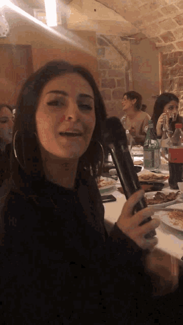 a woman singing into a microphone in front of a table full of food