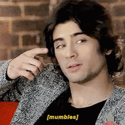 a man in a gray jacket is pointing his finger at himself and the word mubbles is on the bottom of his shirt