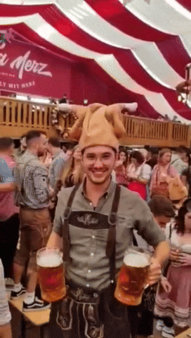 a man wearing a hat and overalls is holding two mugs of beer