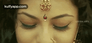 a close up of a woman 's face with a nose ring and a bindi .