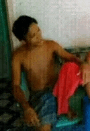 a man without a shirt is sitting on a chair with a red towel around his waist
