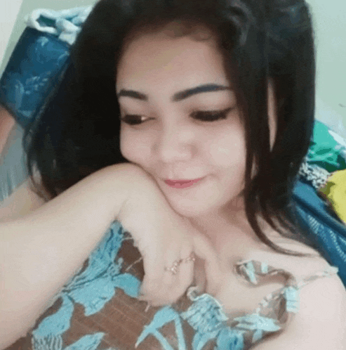 a woman is laying on a bed with her hand on her chest and a ring on her finger .