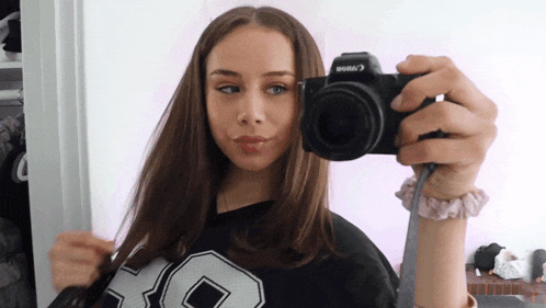 a woman is taking a picture with a canon camera