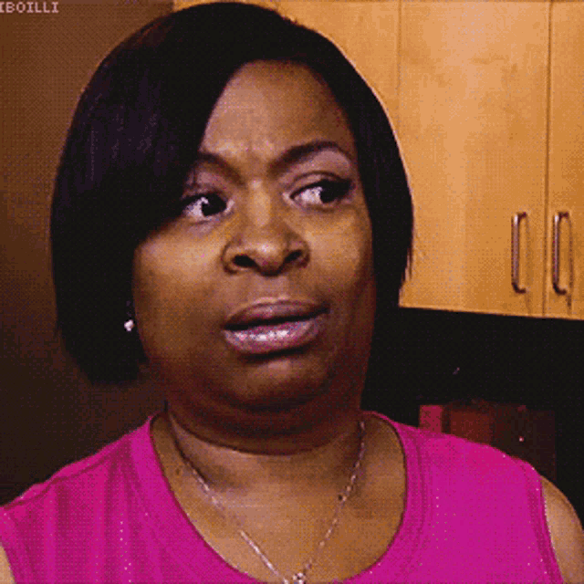 a woman in a pink shirt is making a face