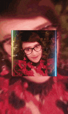 a woman wearing glasses and a red shirt is surrounded by a rainbow light