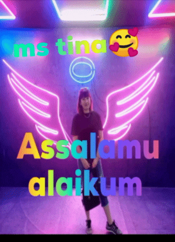 a woman is standing in front of a neon sign that says assalamu alaikum