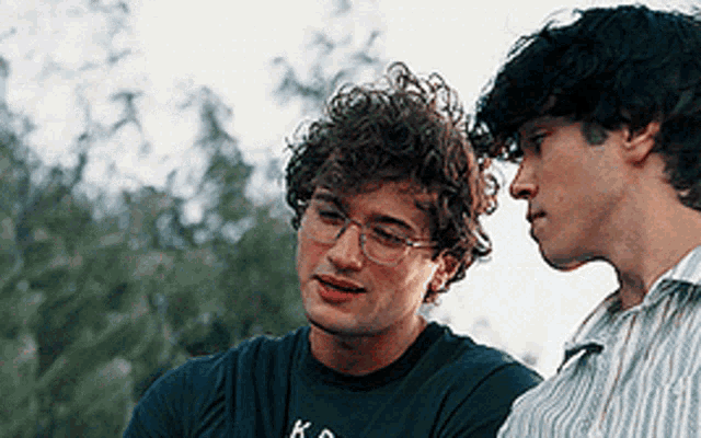 two men are standing next to each other with one wearing a shirt that says k.
