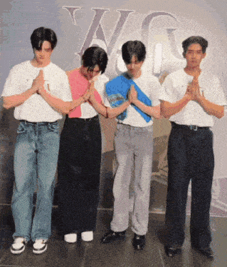 a group of young men are praying in front of a sign that says a