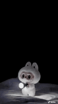 a stuffed animal is holding a flashlight in its hand in the dark .
