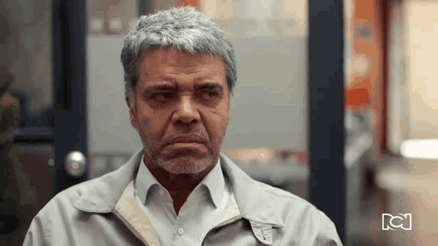 a man with gray hair and a beard is wearing a jacket and a white shirt