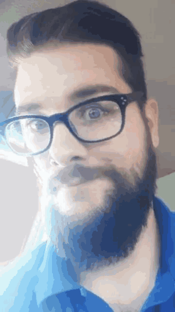 a man with glasses and a beard looks at the camera