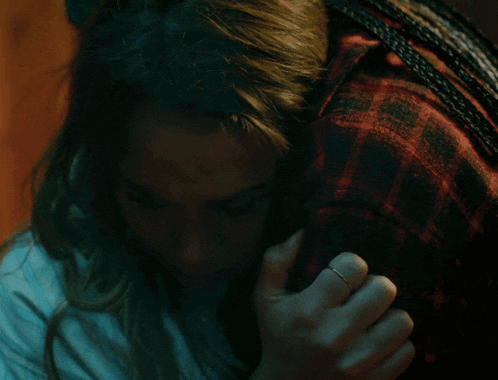 a woman wearing a ring is hugging another woman