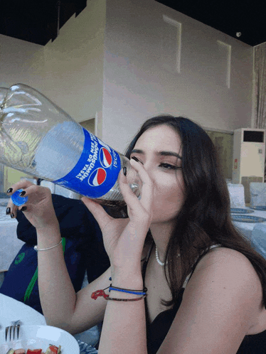 a woman drinking from a bottle that says pepsi on it