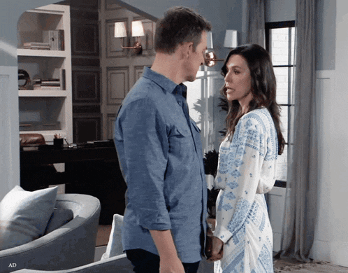 a man and a woman are looking at each other in a living room with ad written on the bottom right
