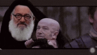 a man with glasses and a beard is holding another man 's head .