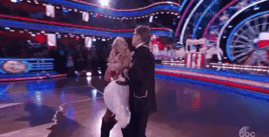 a man is carrying a woman on his shoulders while they dance on a stage .