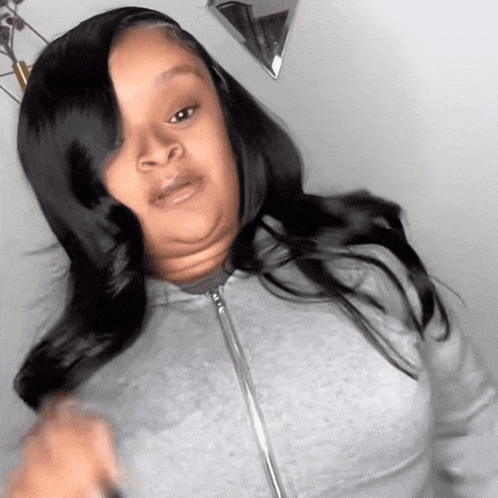 a woman with long black hair is wearing a grey sweatshirt