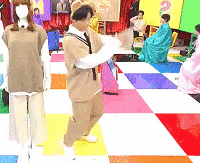 a man is dancing on a colorful checkered floor in front of a sign that says 2