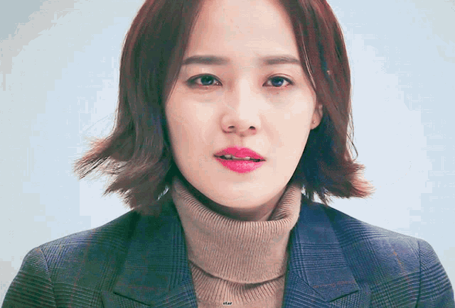 a close up of a woman wearing a turtleneck and a plaid jacket with the word star on the bottom right