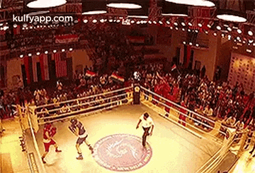 two boxers are fighting in a boxing ring with a referee .