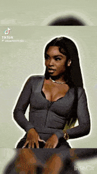a woman is standing in front of a mirror wearing a gray top and a necklace .