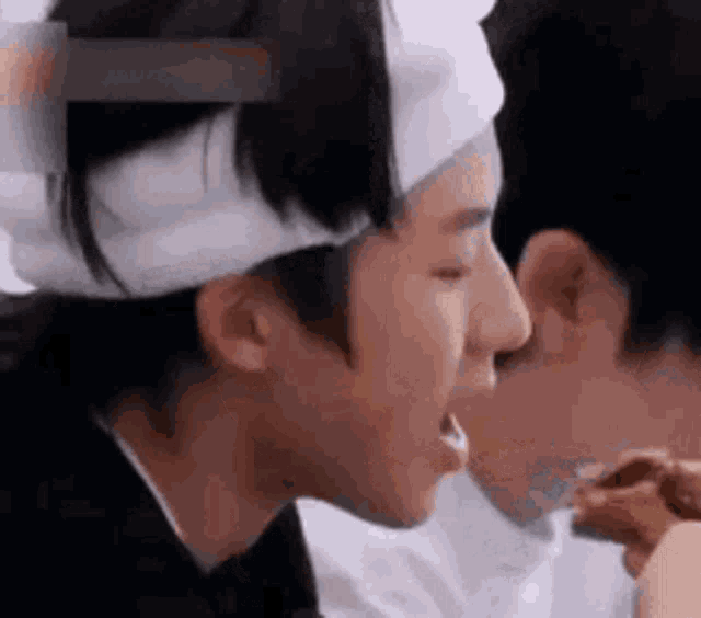 a man and a woman are kissing each other . the man has a bandage on his head .