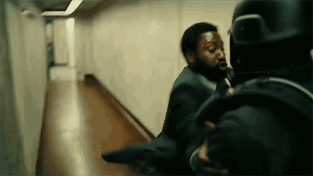 a man in a suit is being thrown by another man in a hallway .