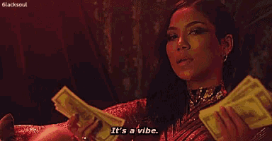 a woman is laying on a couch holding a bunch of money and saying `` it 's a vibe . ''
